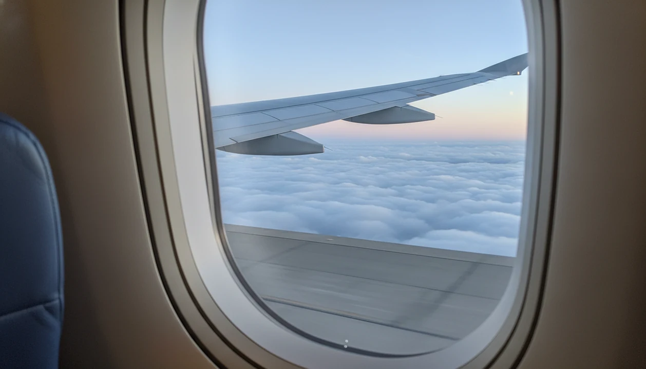 View from an airplane window as the wing rises above the runway during a calm takeoff.